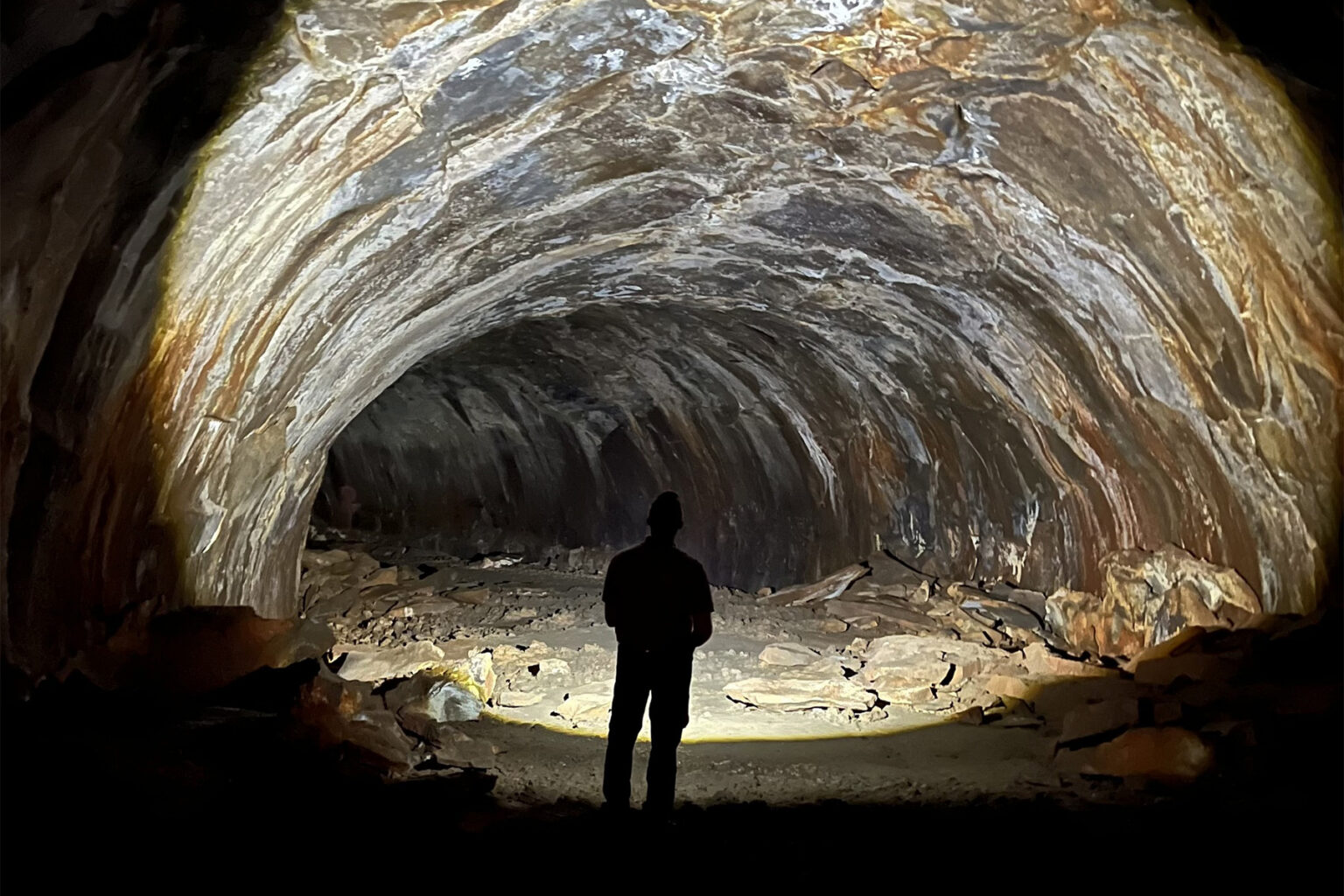 A person wearing a headlamp illuminates Lava River Cave near Flagstaff.