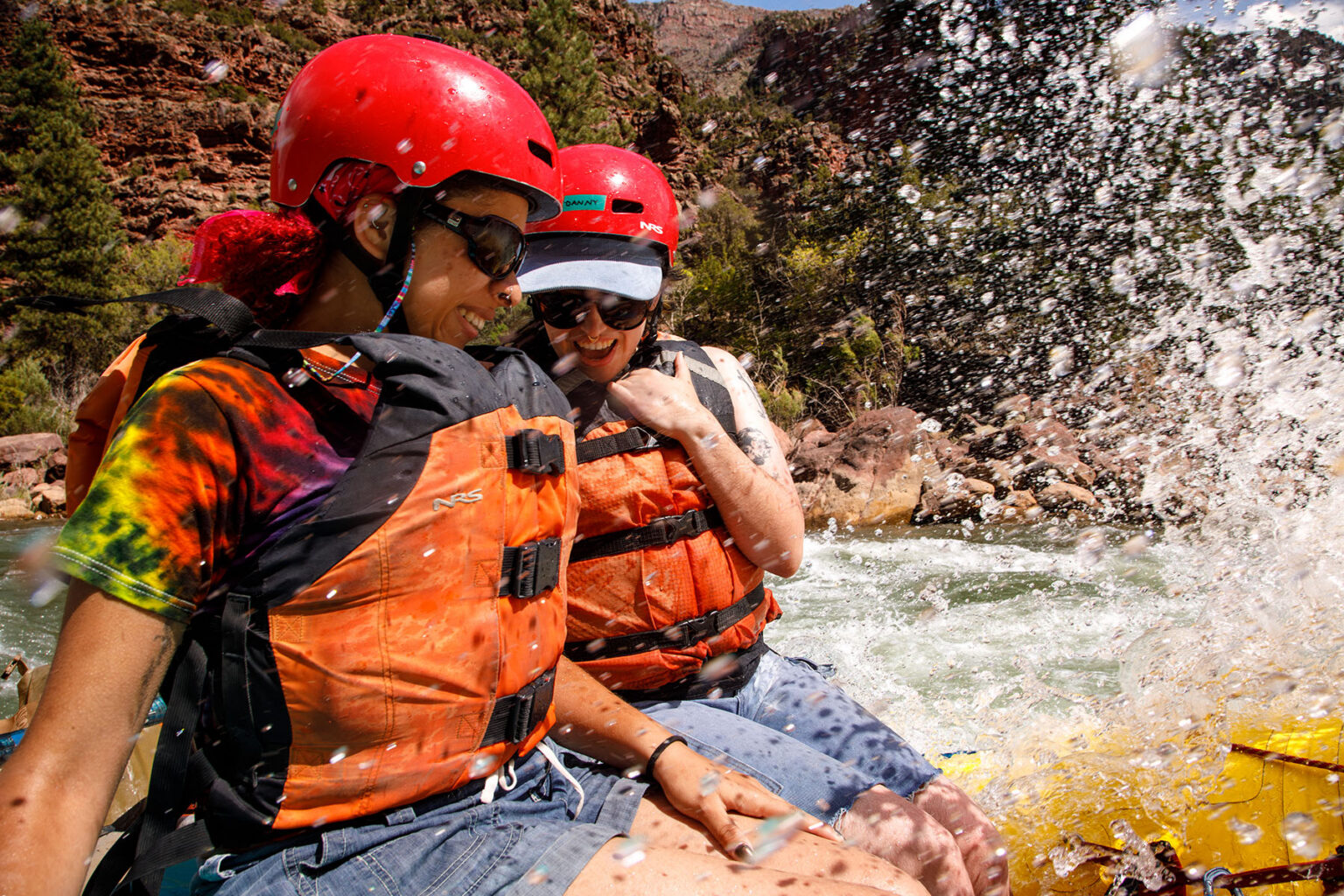 A close-up of two people getting splashed by whitewater
